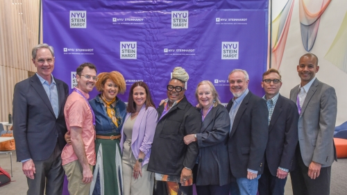 An event photo of nine people posting for the photo in front of an NYU Steinhardt step-and-repeat
