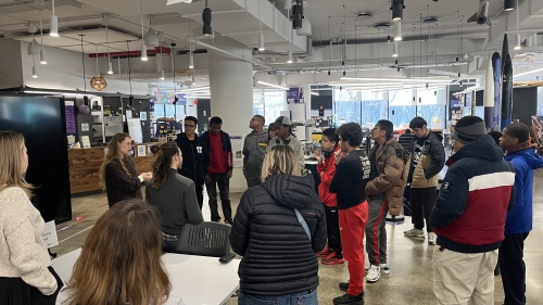 The group stands and listens in a circle