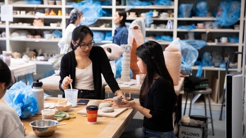 Two students paint their projects.