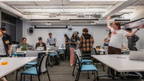 Students stand around a classroom.