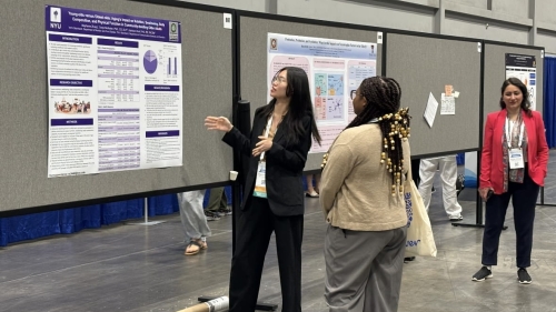 An IMODEL student presents a research poster to an audience member at a conference