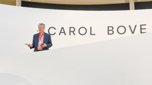 A tour guide stands in front of the Carol Bove sign at the Guggenheim