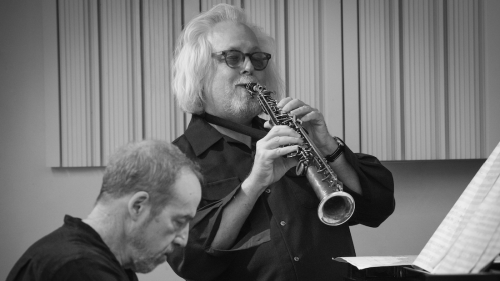 Black and white image of horn and piano players. 