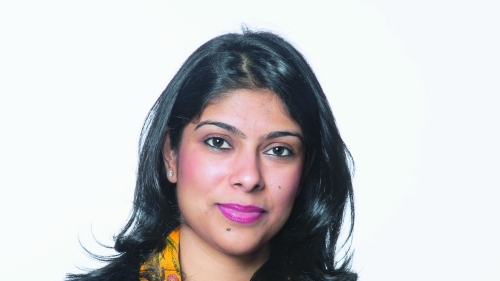 Manjari Sihare-Sutin, an Indian woman in a black shirt with a colorful scarf, looks into the camera with her arms crossed.