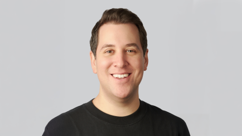 A white male with dark hair smiles at the camera