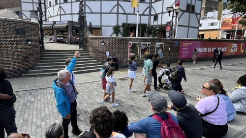 A tour guide points out the Globe Theatre