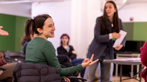 Students in a group looking at one student smiling as she speaks