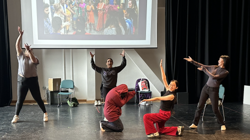 Students doing dance moves in front of pull down screen