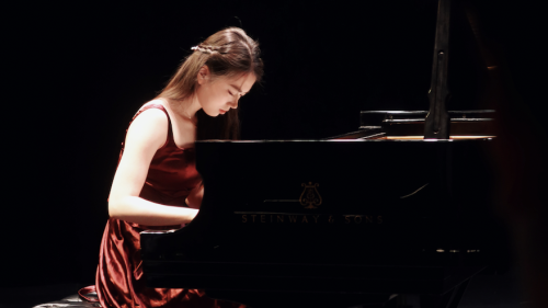 Piano student in red velvet gown performing in Black Box Theatre