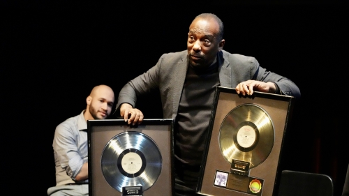 Man holding up a gold and platinum album