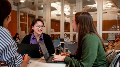 Three students talking around a small table. 