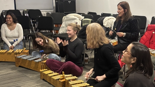 Six students sitting on the floor playing instruments