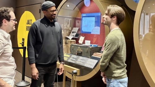 Two students speaking with instructor at Louis Armstrong exhibit