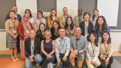 A group of 20 attendees huddle together at the NYU Learning Exchange.