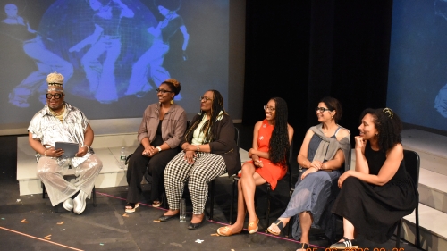Six panelists sit on stage