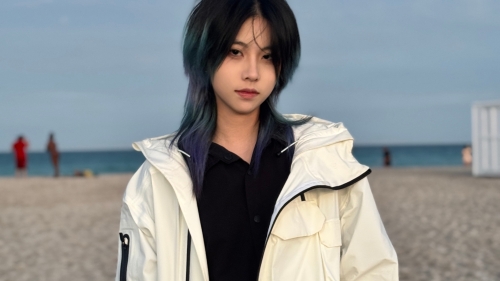 Photo of Pascal Yin on the beach wearing a jacket, ocean in background