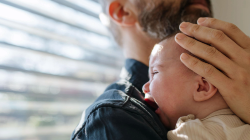 Baby cries on shoulder of father