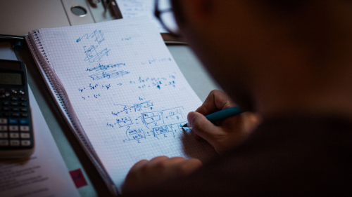A student writes in a notebook