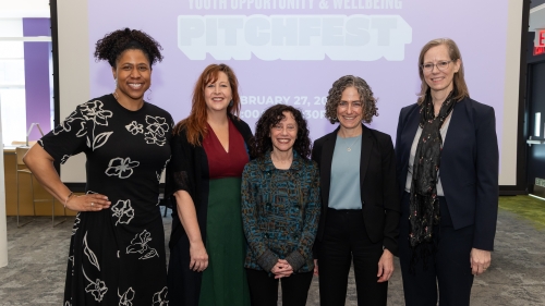 Five Pitchfest judges stand together in a row. From left are Stephanie Cook, associate professor of Global Public Health; Erin Godfrey, director of the Institute of Human Development and Social Change; Mindy Tarlow, senior fellow and research professor at the NYU Marron Institute of Urban Management; Elise Cappella, vice provost for University-wide Initiatives and Graduate Education; and Cheri Fancsali, executive director of the Research Alliance for NYC Schools.