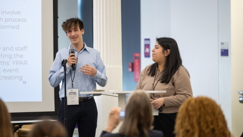 Cooper Halpern, a member of the Youth Advisory Council, speaks at Pitchfest while standing beside Michelle Flores.
