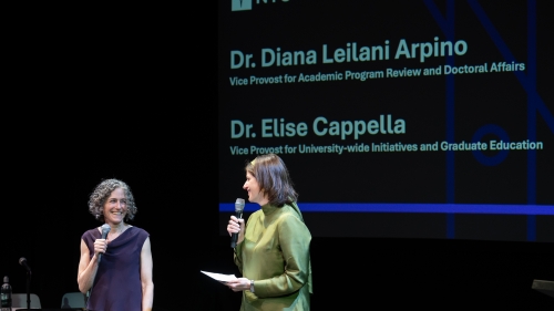 Cappella speaks into a microphone with Diana Arpino
