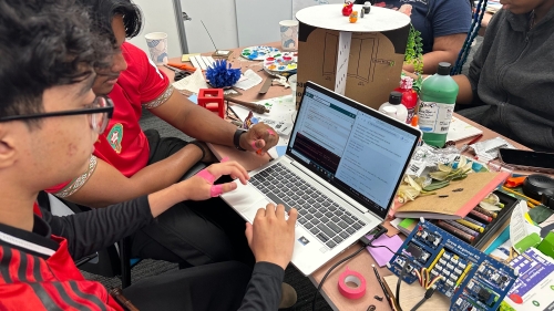 Students sit around a desk with a laptop and diorama supplies