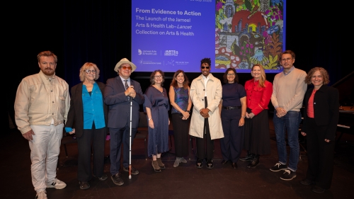 A large group stands under a screen that reads "Healing Arts"