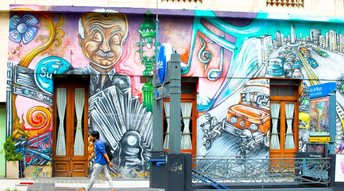 A person walking in front of a wall mural.