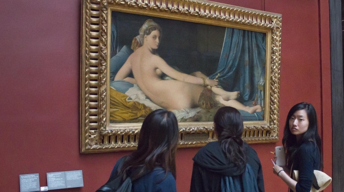 Three people standing in front of artwork of a woman