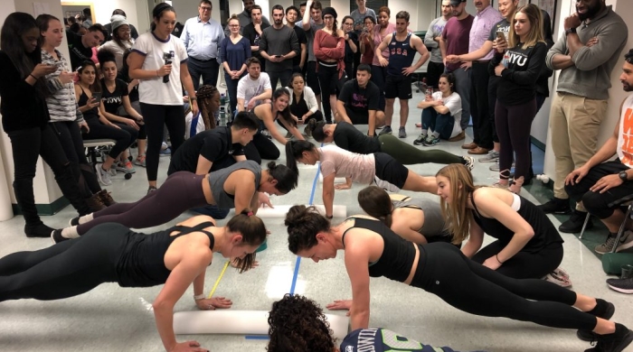 A group of students holding planks while the rest of the competitors watch.
