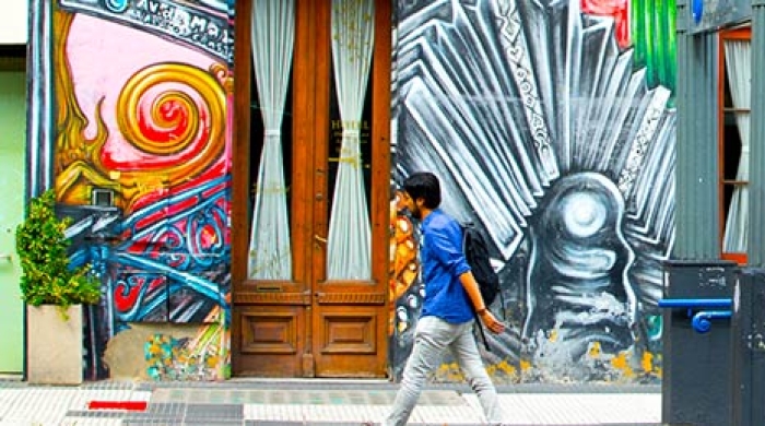 Person walking in front of building with art work