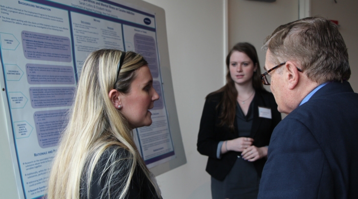 Student talking to faculty in front of poster