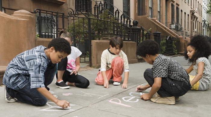 Five children drawing on sidewalk with chalk