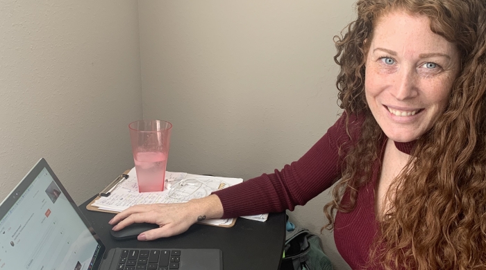 Erin Dotzel sitting in front of a laptop smiling at the camera.