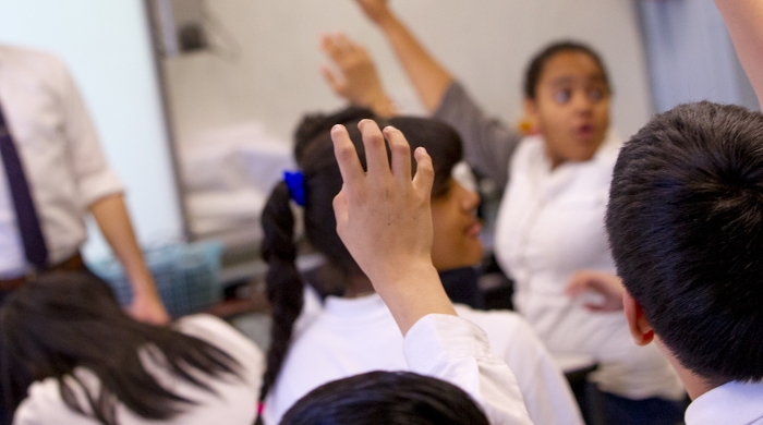 Kids raising hands in a classroom