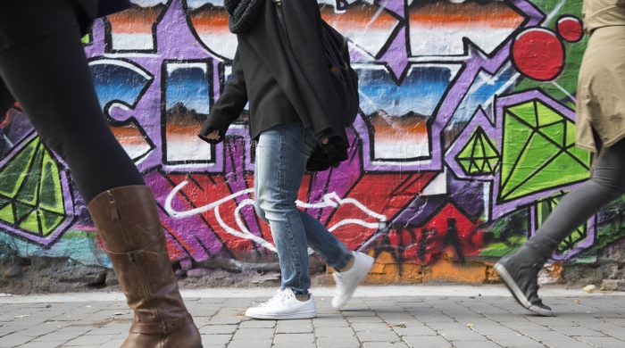 Pedestrians walking past graffiti on an East Village wall
