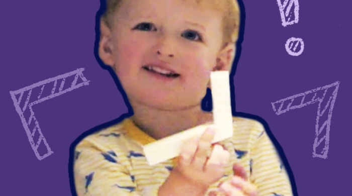 A toddler holding up an angle cut out of paper