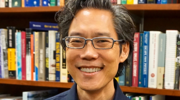 Headshot of Hirokazu Yoshikawa in front of bookshelf
