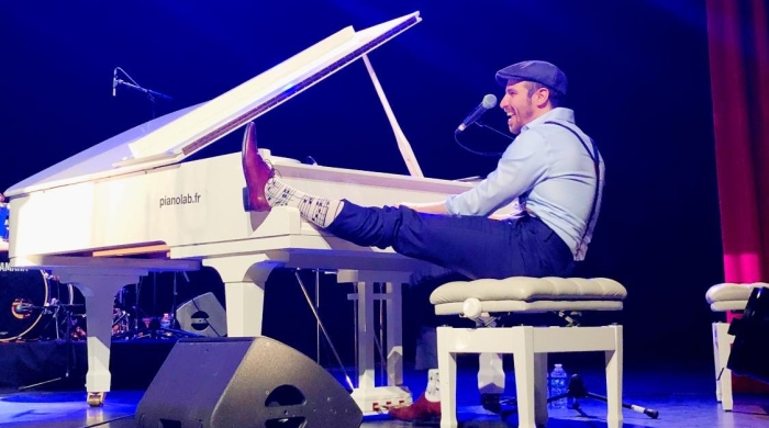 Arthur seated at a piano with one leg perched on the keys.