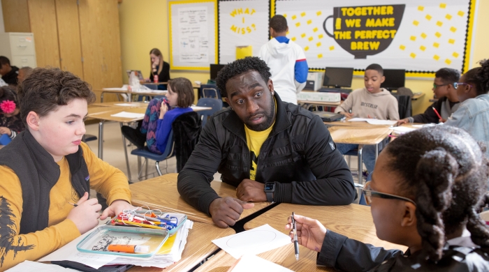A black teacher works with a white student and a black student in a small group
