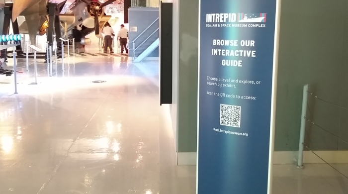 A sign at the Intrepid Museum with a QR code for access to an interactive museum guide.