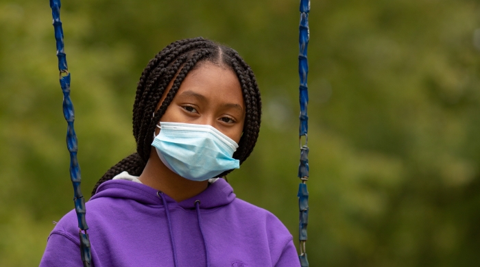 A remote learning student works on an assignment on the swing set.