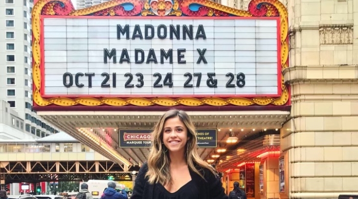 Brittney posing in front of a marquee that reads "Madonna Madame X Oct 21 23 24 27 & 28"