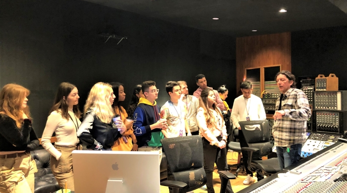 A group of NYU students receiving a tour of a local music study by a guide.