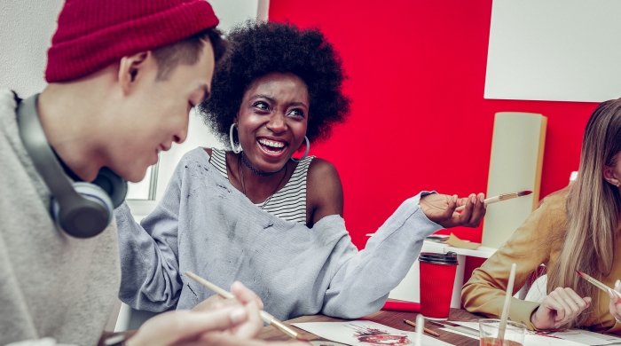 3 art students at a table painting