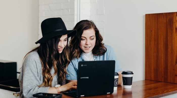 Two people at a table looking at a laptop.