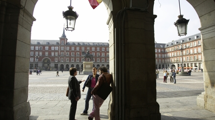 Three students stand and talk in the Plaza Mayor in Madrid, Spain.