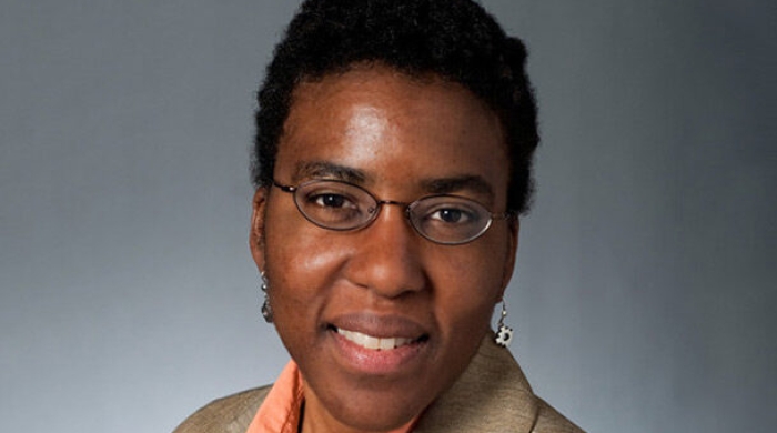 A headshot of Anne Washington, a Black woman with glasses smiling at the camera. 