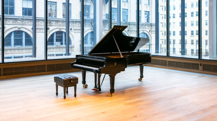 A Steinway concert piano sits in the glass-walled Paulson Center rehearsal room.