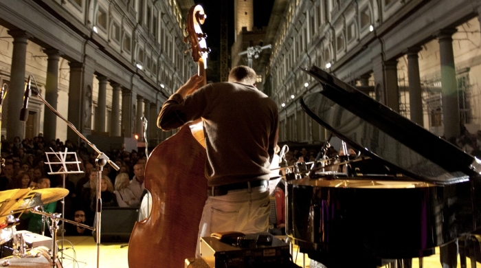 A performer playing a stand-up bass in front of a large audience